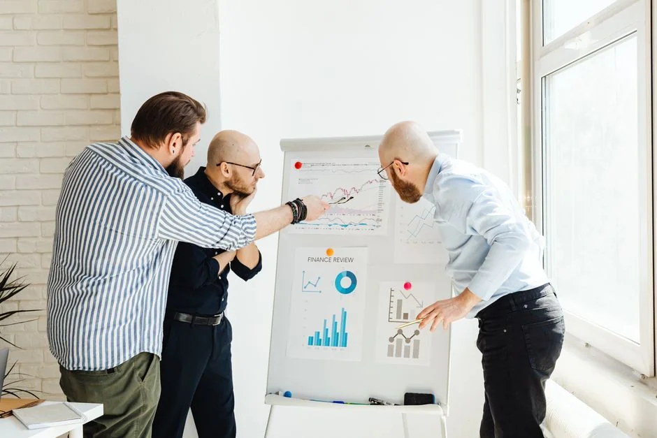 Vue plongeante d’une équipe discutant de stratégies de marketing digital avec des ordinateurs portables et des graphiques.